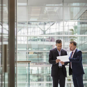 Businessmen discussing project on office balcony Kostenkontrolle